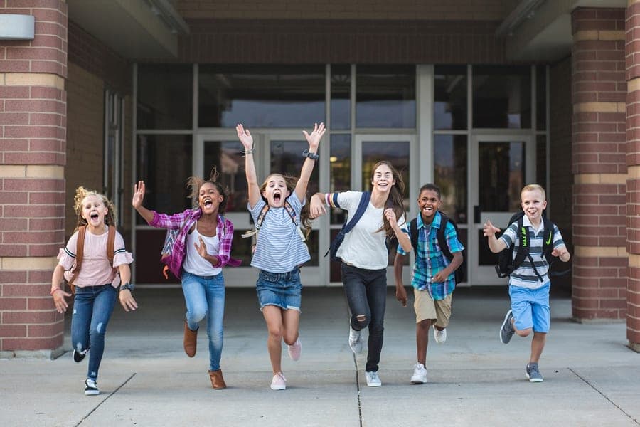 Students joyfully running together outside school